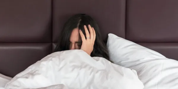Una mujer con las manos en la cabeza despierta de una pesadilla 