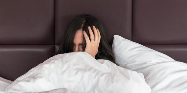 Una mujer con las manos en la cabeza despierta de una pesadilla 