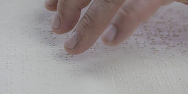 Mano de una persona con discapacidad visual leyendo en Braille