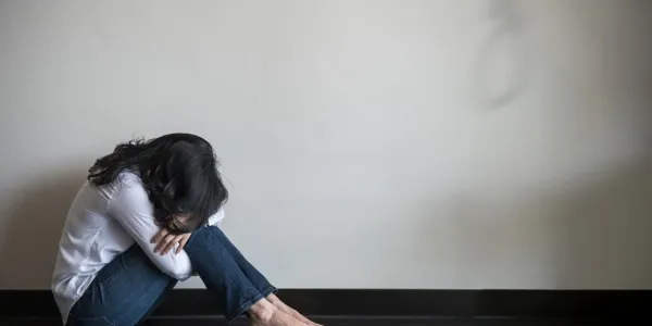Chica encogida en el suelo y llorando