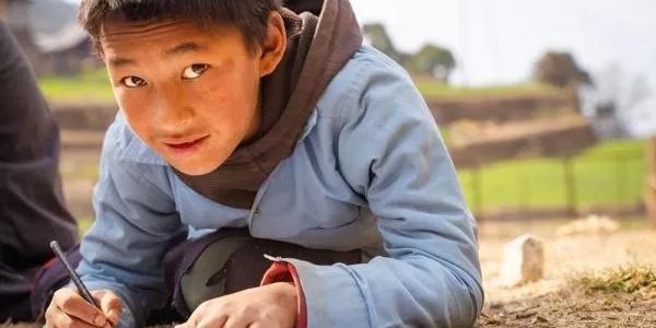 Niño de otro país haciendo deberes en la calle