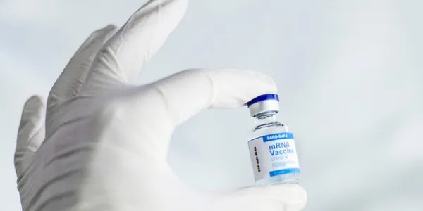Mano de un sanitario con guante sujetando la vacuna covid