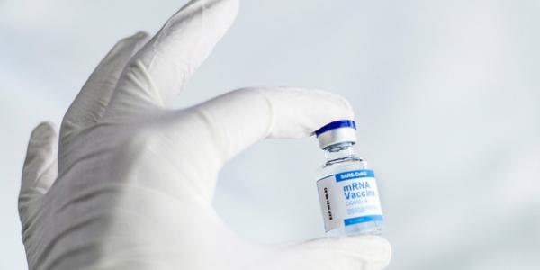 Mano de un sanitario con guante sujetando la vacuna covid
