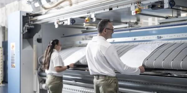 Dos personas con discapacidad e su puesto de trabajo en Ilunion TextilCare.