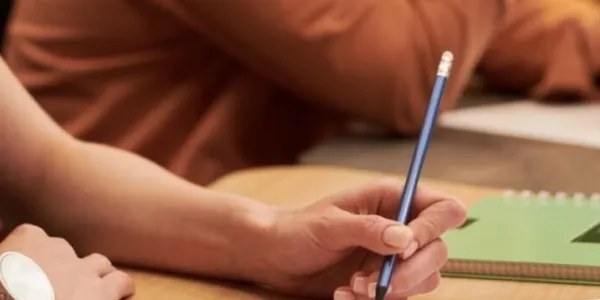 Una chica con un lápiz escribiendo a mano