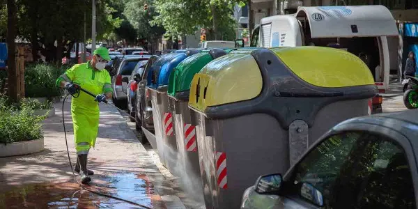Operario de limpieza del servicio municipal desinfecta un contenedor amarillo de residuos
