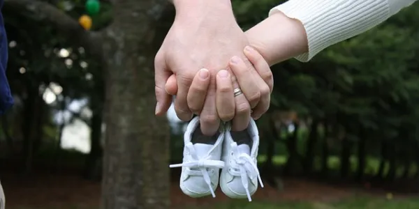 Manos de dos personas sosteniendo unos zapatos de bebé