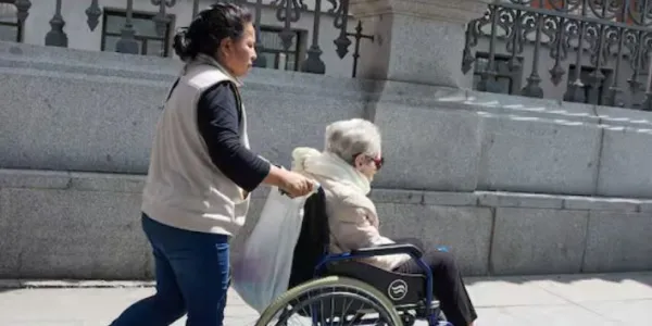 Mujer extranjera cuidado de una persona dependiente en silla de ruedas