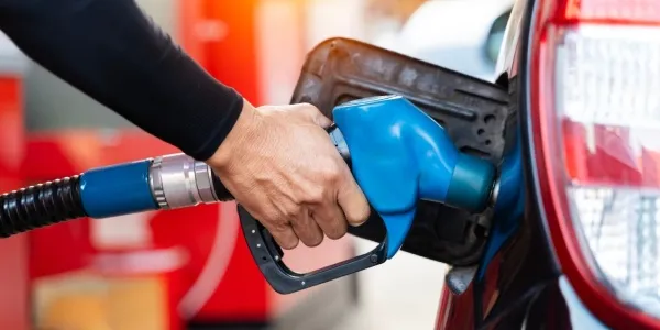 Mano de una persona echando gasolina barata a su coche