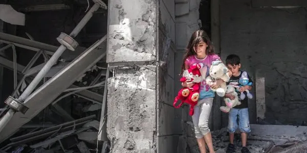 Niños palestinos recogiendo sus juguetes de su hogar destrozado en Gaza