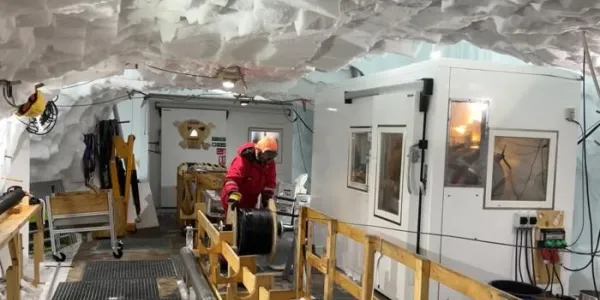 Un investigador baja un cable de fibra óptica dentro de un pozo para registrar señales del interior de la corriente de hielo en Groenlandia