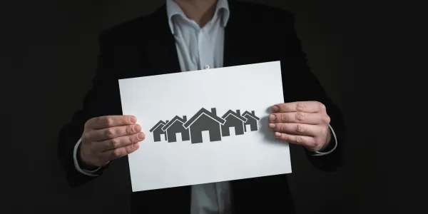 Infografía de un chico sosteniendo un cartel con varias casas dibujadas