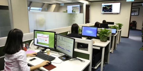 Sala de una oficina con personas trabajando en sus puestos de ordenadores