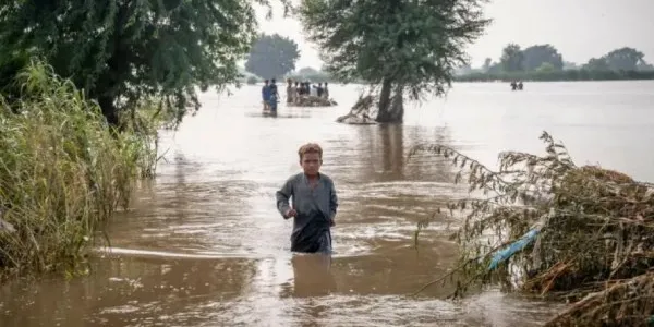 Un niño camina en medio de una calle inundada