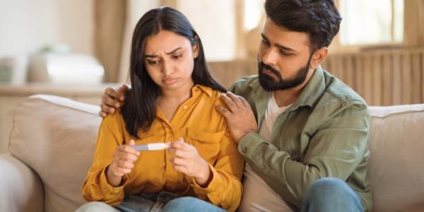 Parejas tristes mirando un test de embarazo negativo