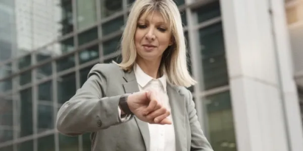 Mujer mirando el reloj a la hora de salir de la oficina