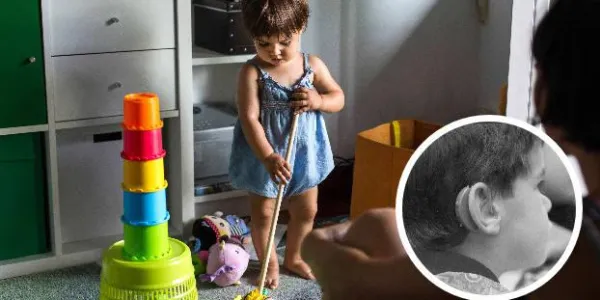Una niña jugando. A la derecha, un niño pequeño con un audífono. / EL NORTE