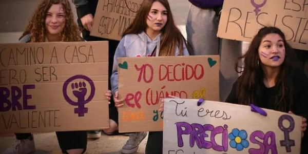 Tres jóvenes sujetan carteles en una manifestación feminista