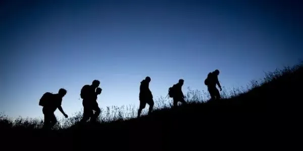Silueta de 5 personas escalando una montaña