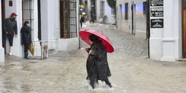 Una vecina de Grazalema (Cádiz) camina por una calle inundada debido a las intensas lluvias.