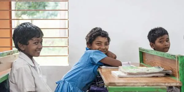 Una niña de la comunidad, sentada junto a sus compañeros de clase. 