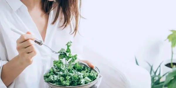 Una mujer comiendo vegetales. 