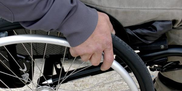 Mano de una persona en su silla de ruedas