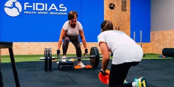 Dos personas entrenando en el gimnasio con pesas