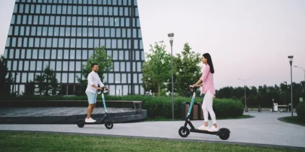 pareja diversa montando patinetes en la calle
