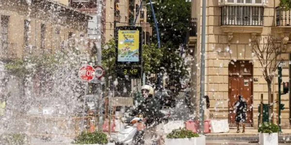 Chico en una moto frente a una fuente y  un termómetro que marca 34 grados