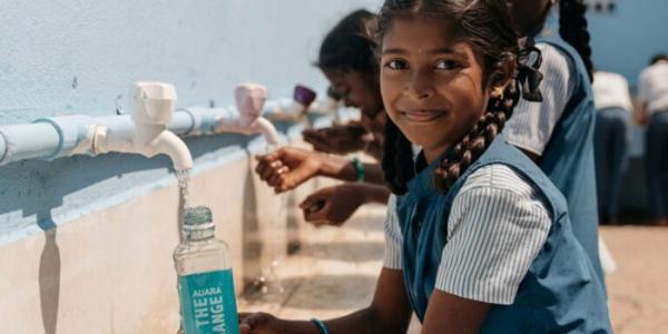 Niña llenando una botella de agua