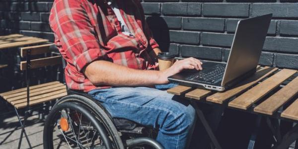 Un hombre con discapacidad consulta en un ordenador portátil 