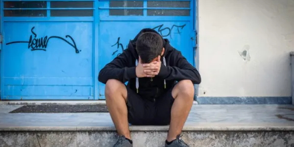 Un joven vulnerable, sentado en unas escaleras 