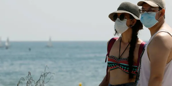 Personas llevando la mascarilla en la playa