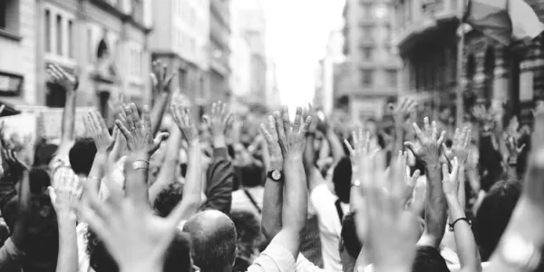 Fotografía en blanco y negro que muestra los brazos en alto de muchas personas en una manifestación