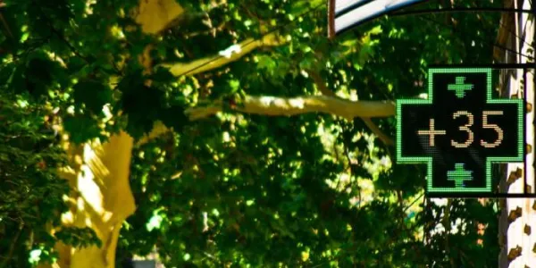Una cruz verde de una farmacia indica una temperatura de 35 grados
