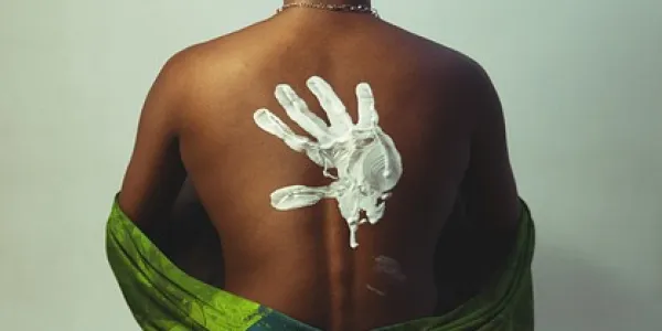 Chica de raza negra con una mano blanca pintada en la espalda