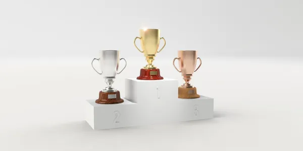 Es un pódium blanco con tres copas colocadas en orden de ganador