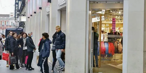 n grupo de clientes hace cola para entrar a un establecimiento de moda.