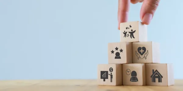 Imagen con cubos de madera formando una torre y la mano de una chica