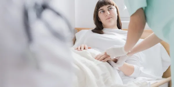 Una mujer joven mira a una profesional sanitaria que le toma el pulso 