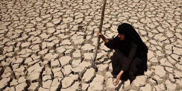 Mujer siria sentada en un suelo desértico por la sequia