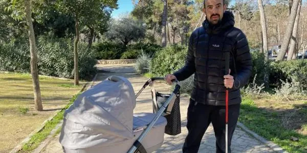 Javier con su bastón y el carrito de su hijo pequeño.