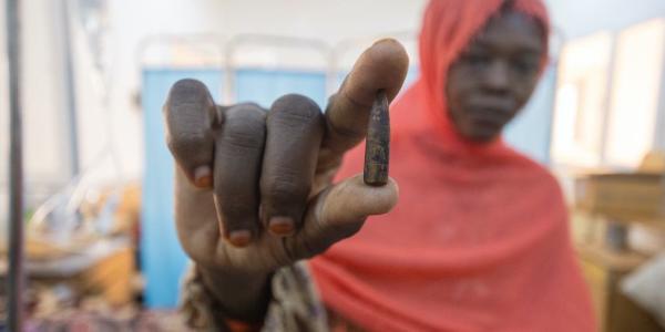 Una madre sostiene la bala que le extrajeron a su hija de ocho años después de que fuera alcanzada en su casa en las afueras de la capital, Jartum.