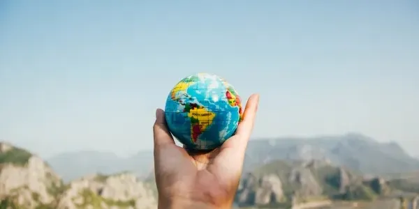 Mano de una persona sujetando una pelota con forma de mundo
