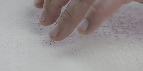 Mano de una persona leyendo en Braille