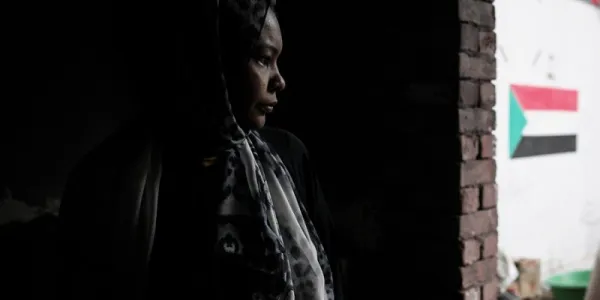 Foto de una mujer sudanesa esperando autobuses organizados para su retorno voluntario desde Egipto a Sudán