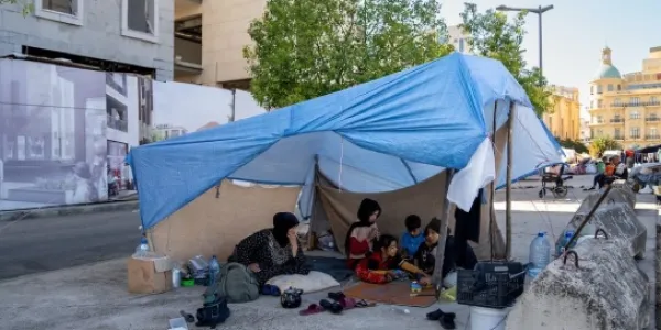 Una madre y sus hijos se refugian bajo una lona en Beirut tras verse obligados a abandonar su hogar.