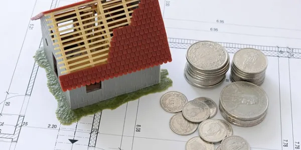 Imagen de una casa y monedas simbolizando el ahorro para comprar una vivienda
