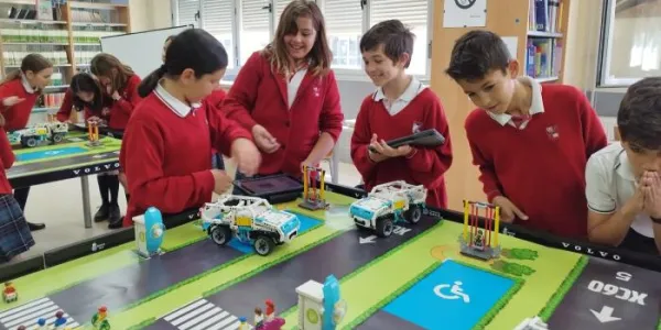 Foto de escolares trabajando en un proyecto en el que se ven vehículos, pasos de cebra y plazas de aparcamiento reservadas a personas con discapacidad